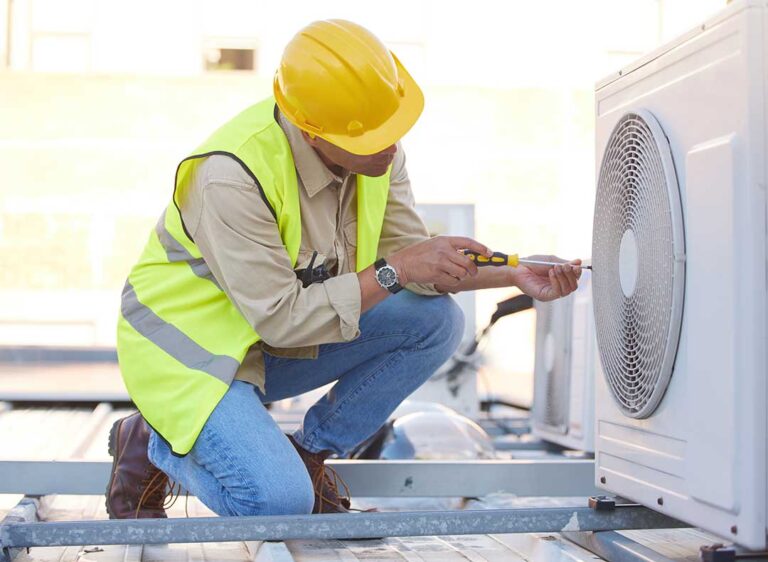 A person adjusting a home thermostat while a window shows condensation droplets in the background.